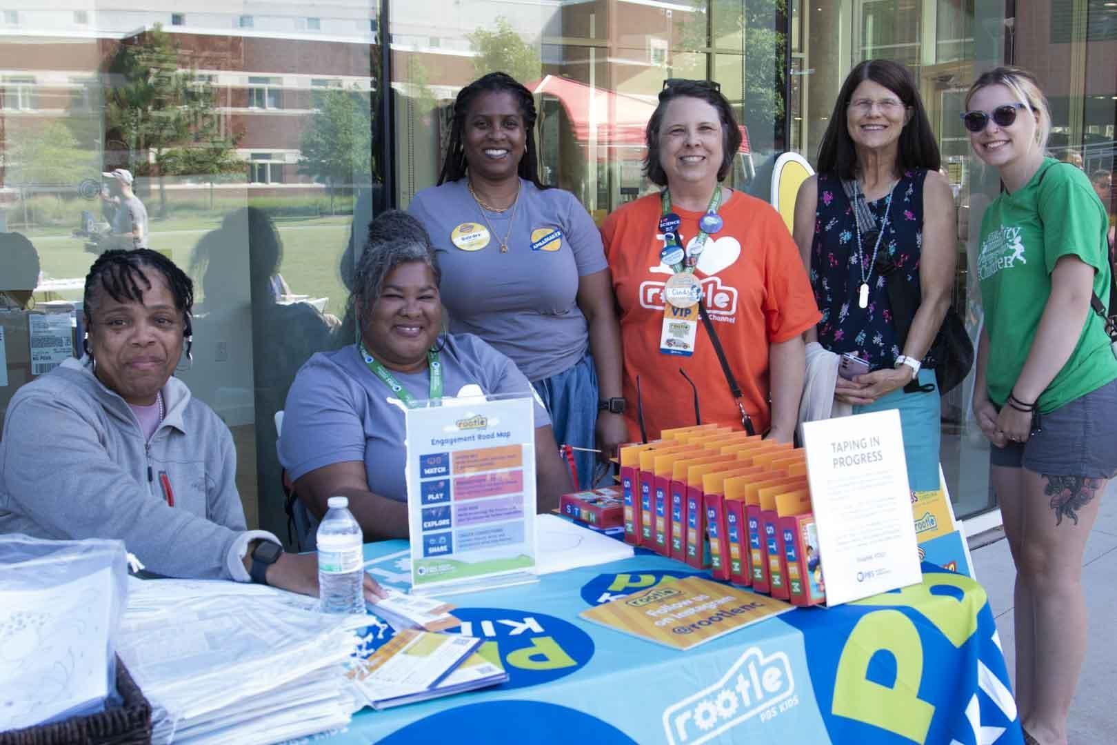 PBS North Carolina Education team members pose with Rootle Ambassadors at a PBS KIDS table at a Rootle Roadster Tour stop.