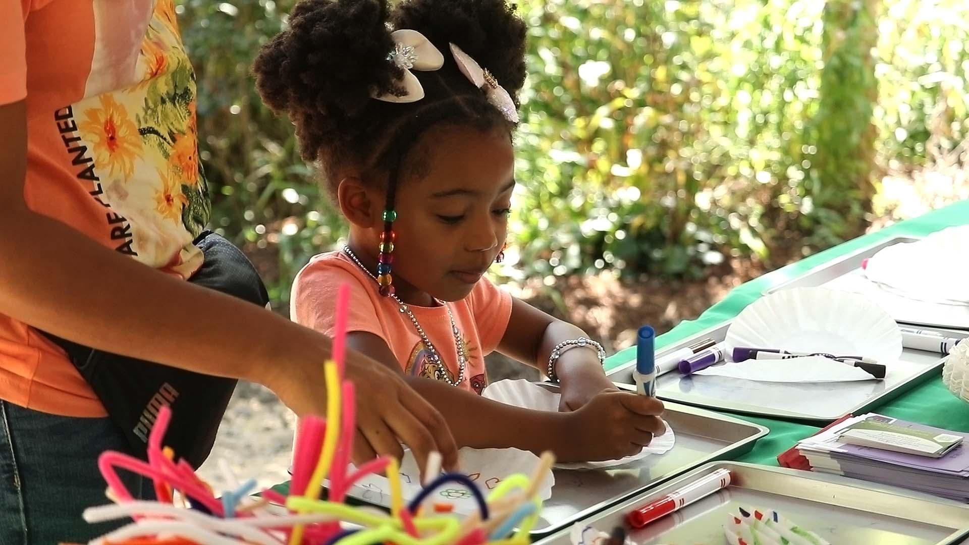 Close up of a child drawing on a coffee filter at a Rootle Roadster Tour craft table.