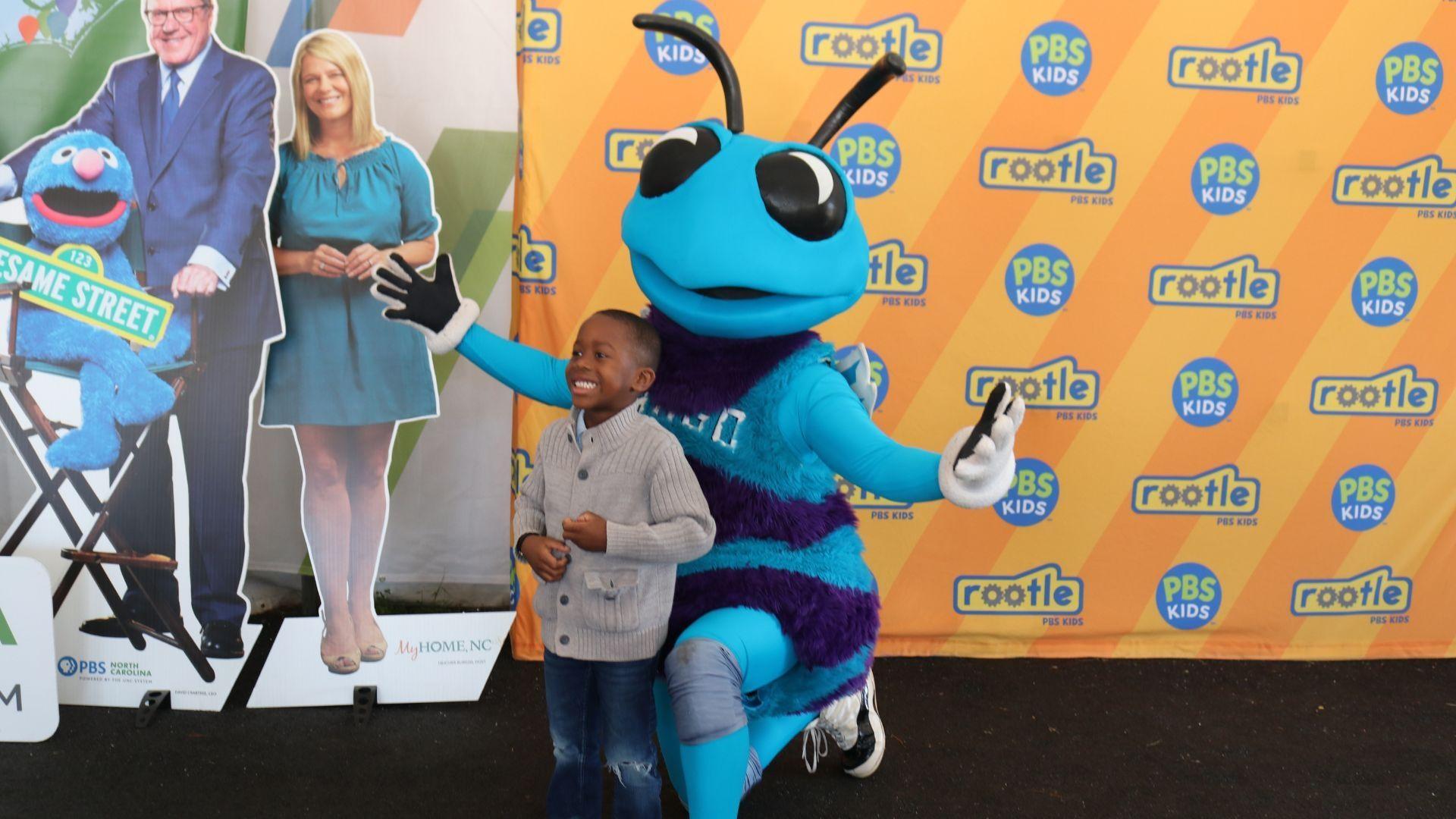 A little boy poses with Hugo Hornet at a Rootle Roadster Tour stop.