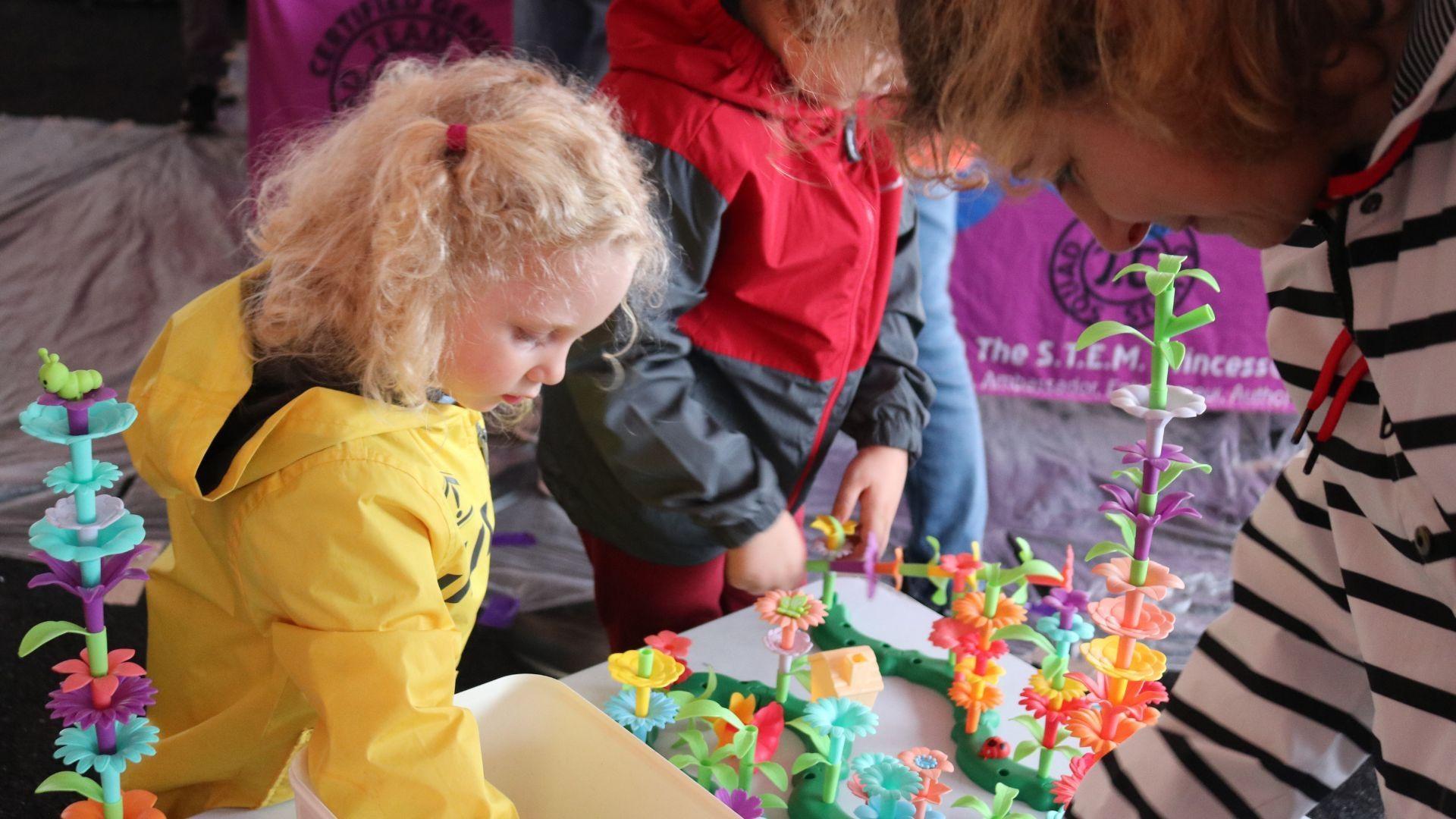 A little girl plays with plastic flower pieces at a Rootle Roadster Tour stop.