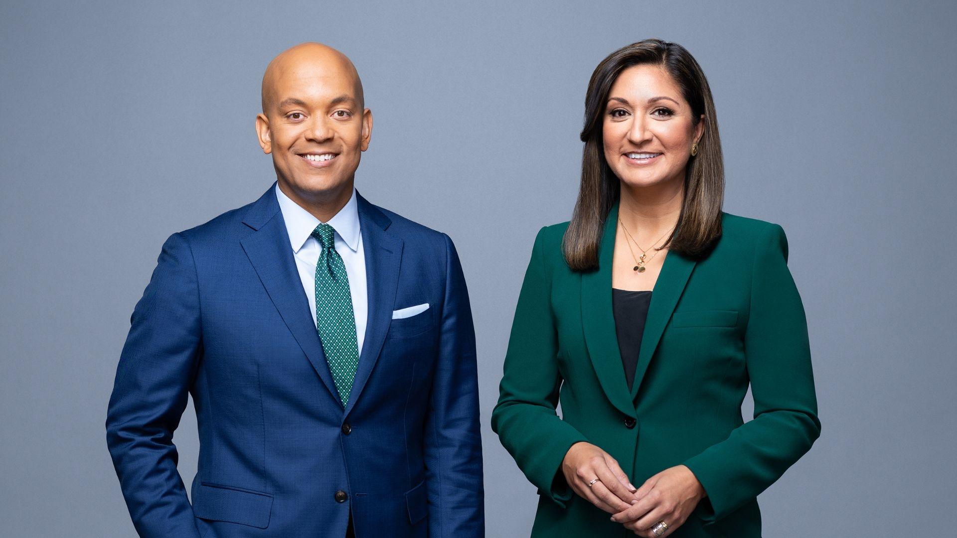 Hosts of PBS NewsHour, Geoff Bennett and Amna Nawaz stand in front of a grey background.