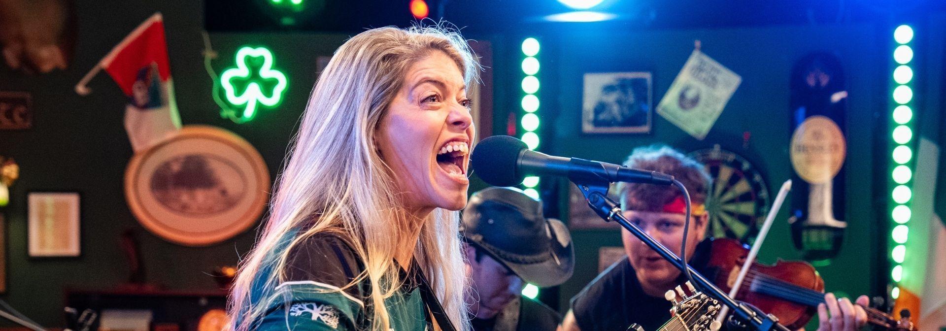 Courtney Barefoot of Tan and Sober Gentleman singing into a mic.