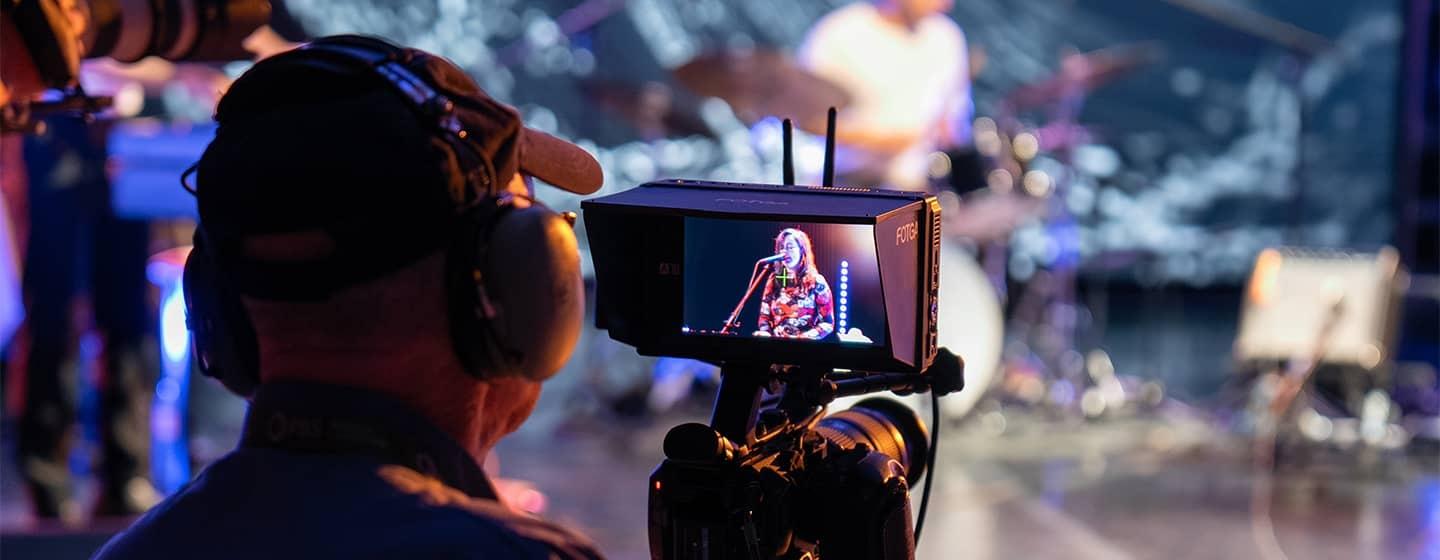 Camera operator filming a musician in the studio.