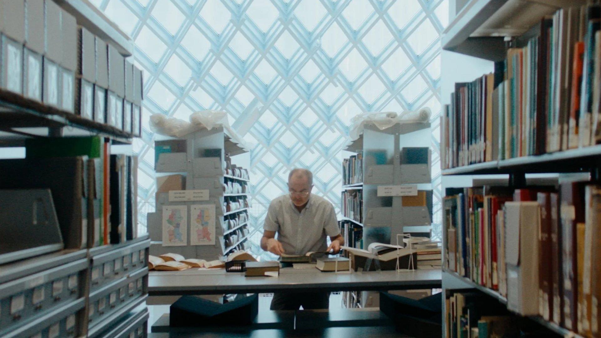 Filmmaker, Paul Bonesteel at a library table covered in books.