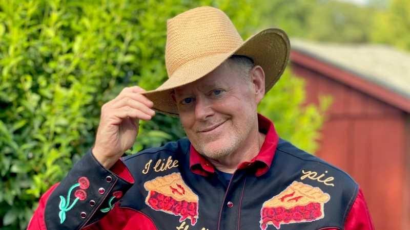 Brian Noyes wearing a button up shirt with pie images and a light tan hat