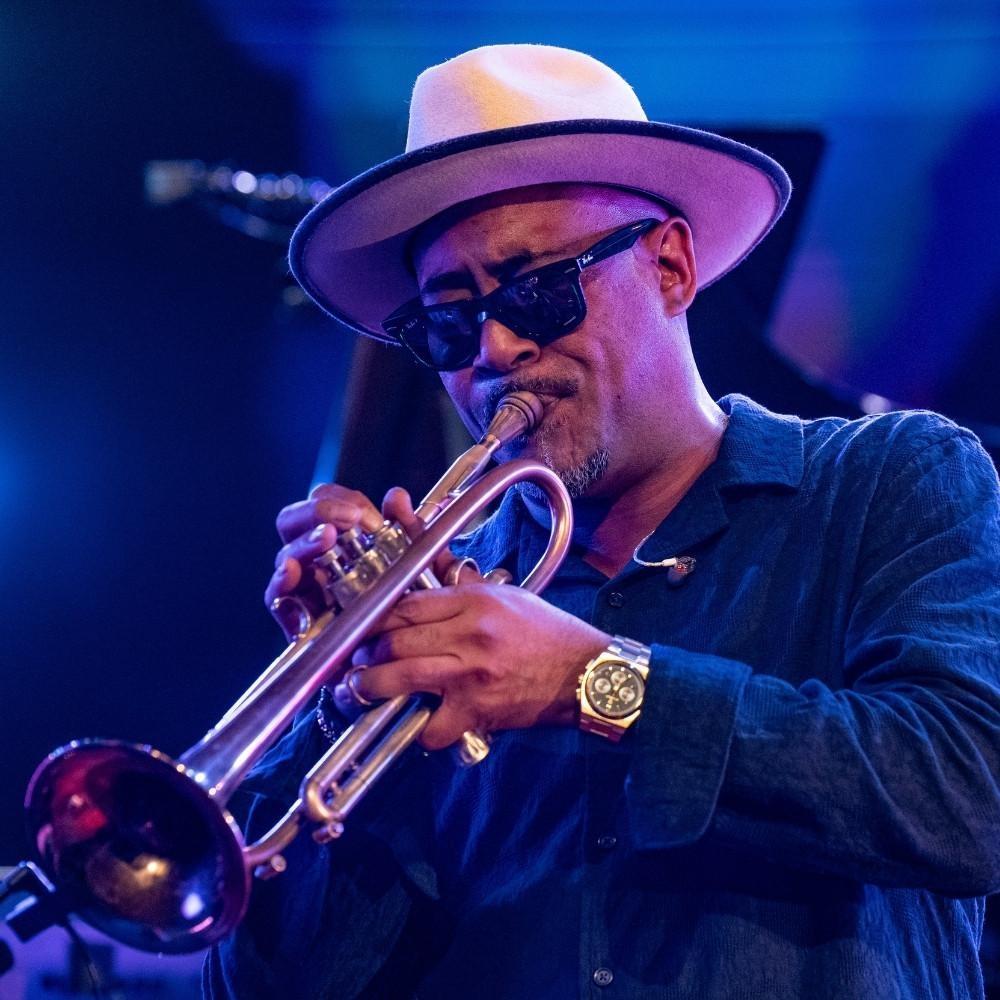 Al Strong playing a trumpet while wearing sunglasses and a fedora.