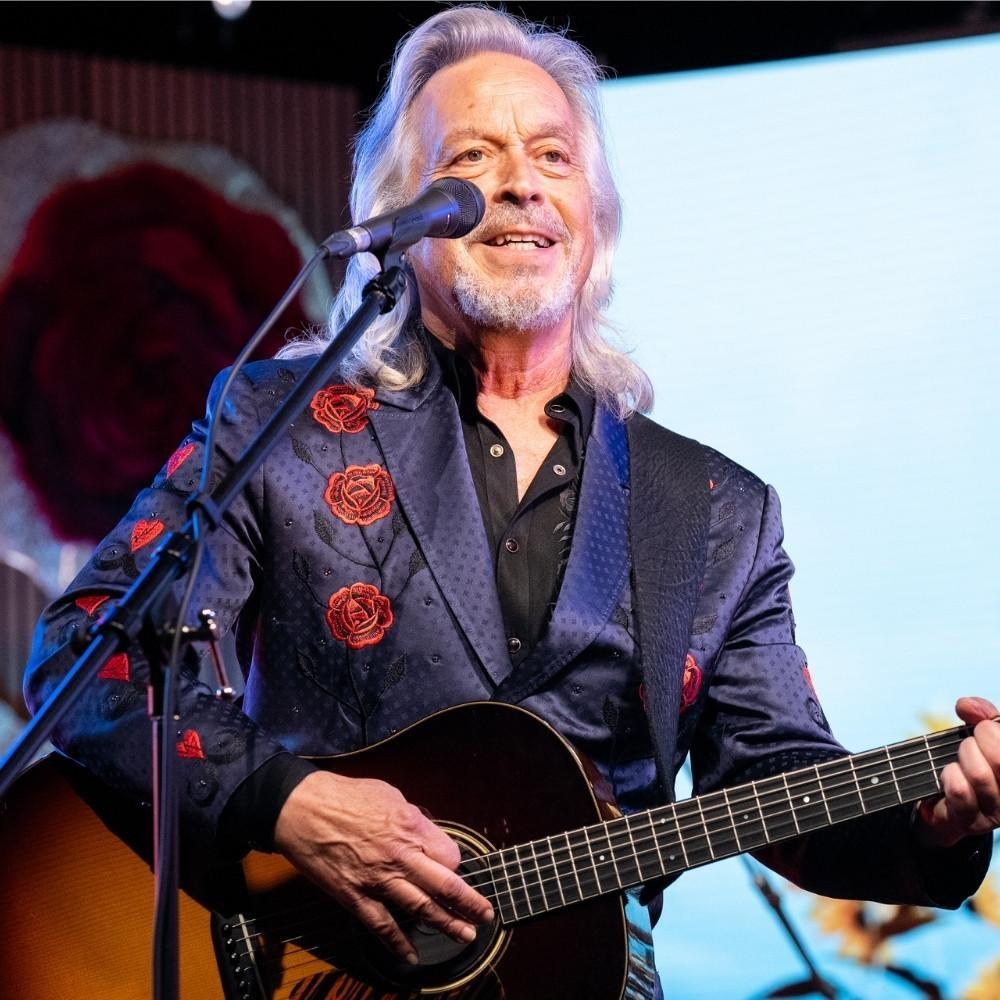 Jim Lauderdale playing guitar and singing into a microphone.