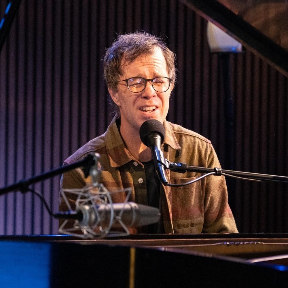 Ben Folds behind a piano on the set of Shaped by Sound.