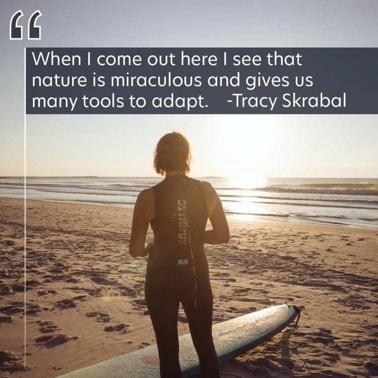 Tracey faces the ocean with her surfboard. Text is "When I come out here I see that nature is miraculous and gives us many tools to adapt." -Tracy Skrabal