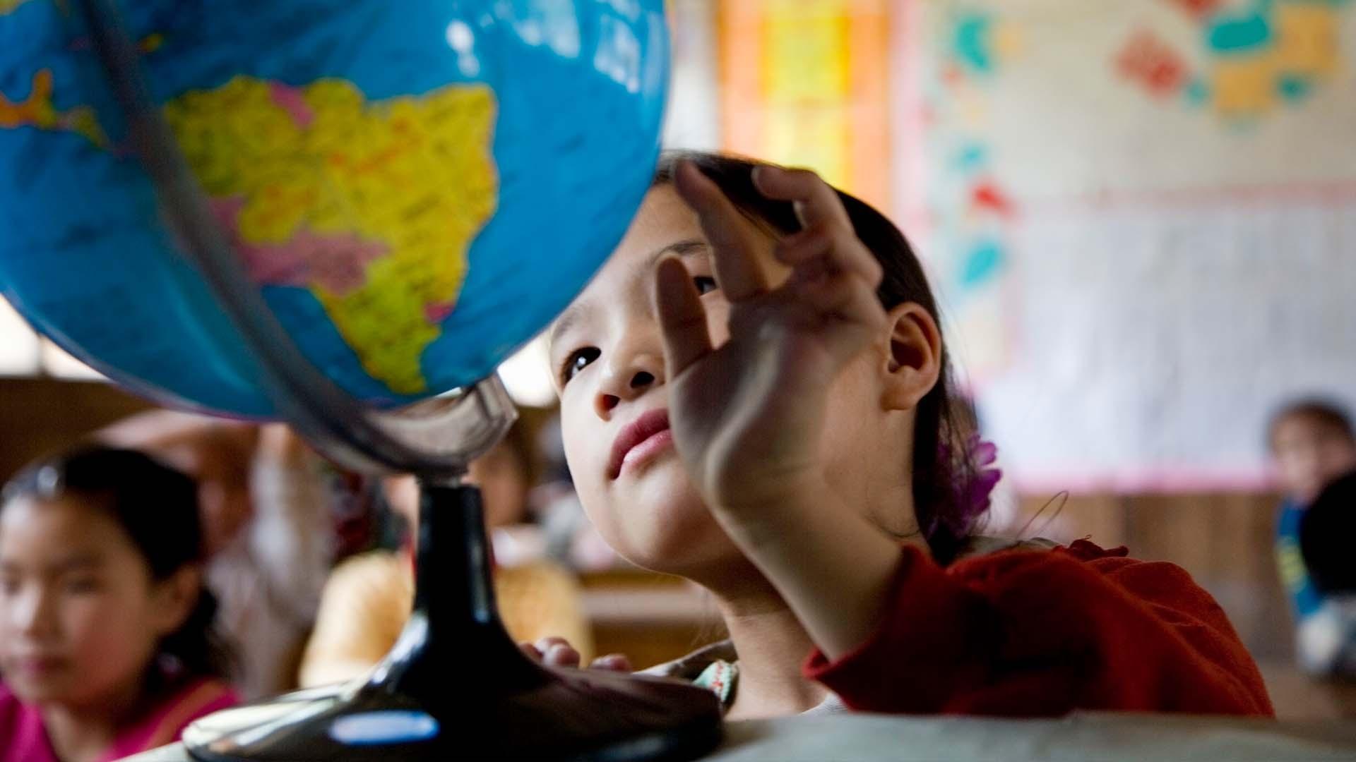 Child observing a map globe in class