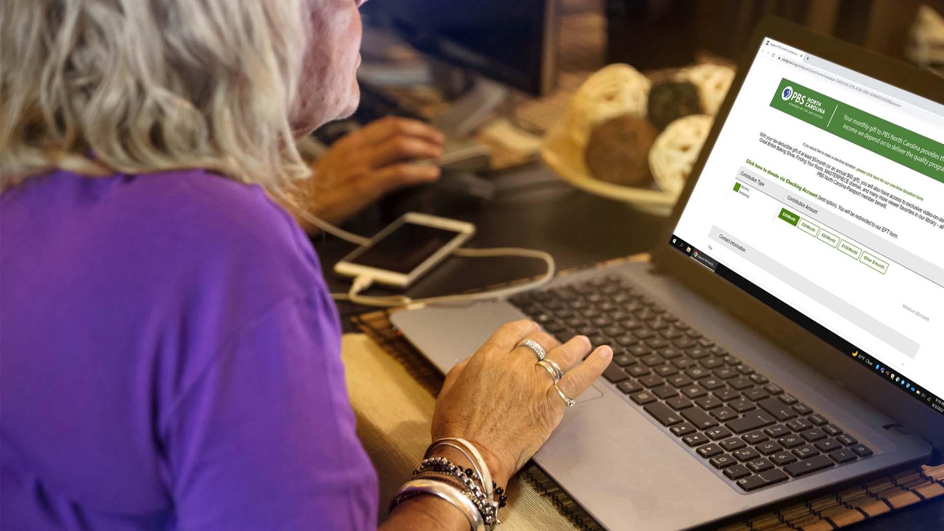 elderly woman typing on a laptop renewing PBS membership