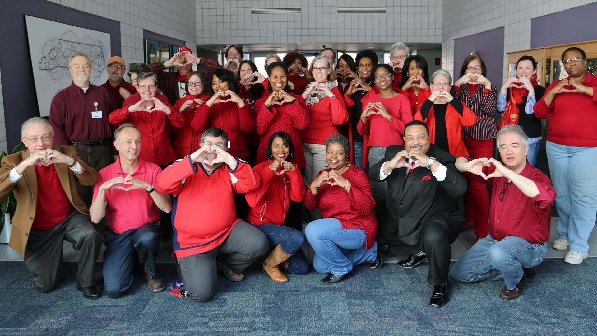 PBS employees holding heart shapes with their hands