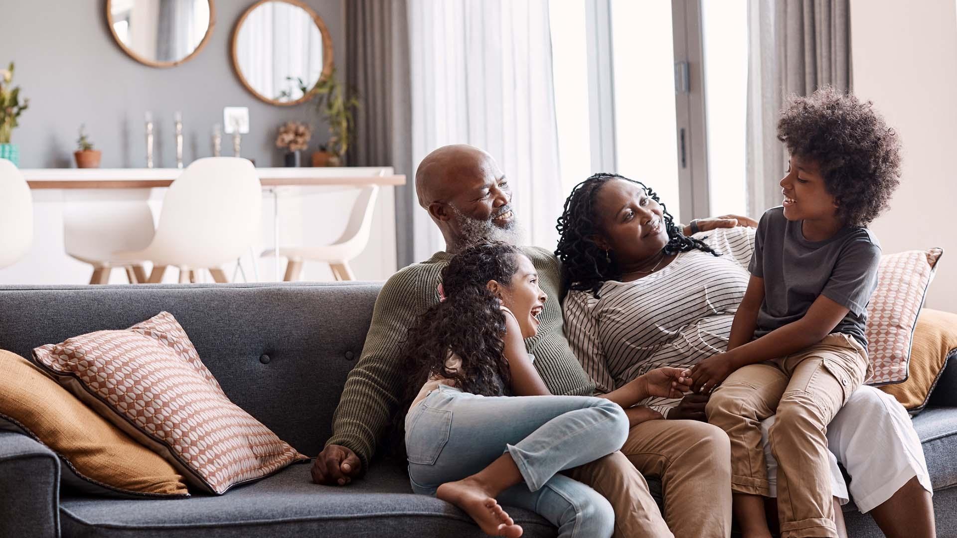 Black family grandparents and grandchildren happily talking on the couch