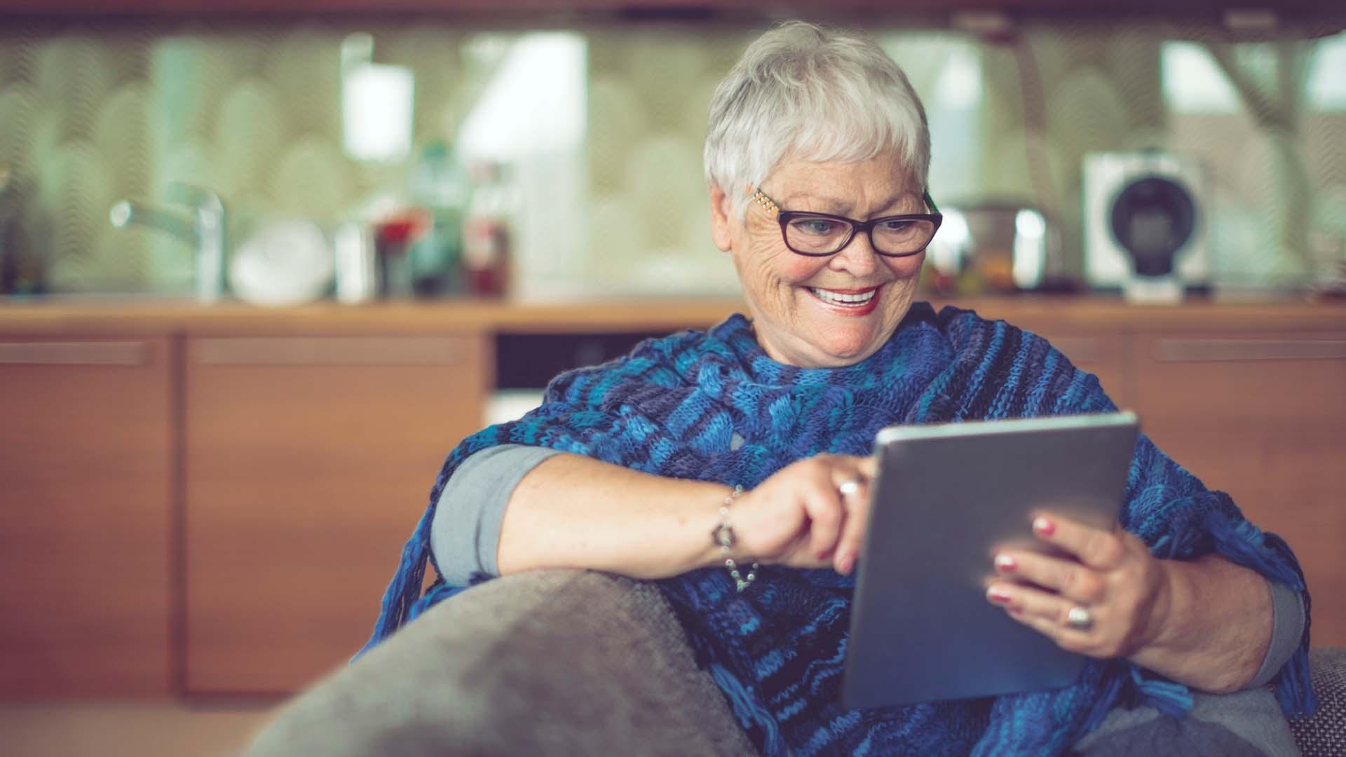 Elderly woman smiling looking at tablet