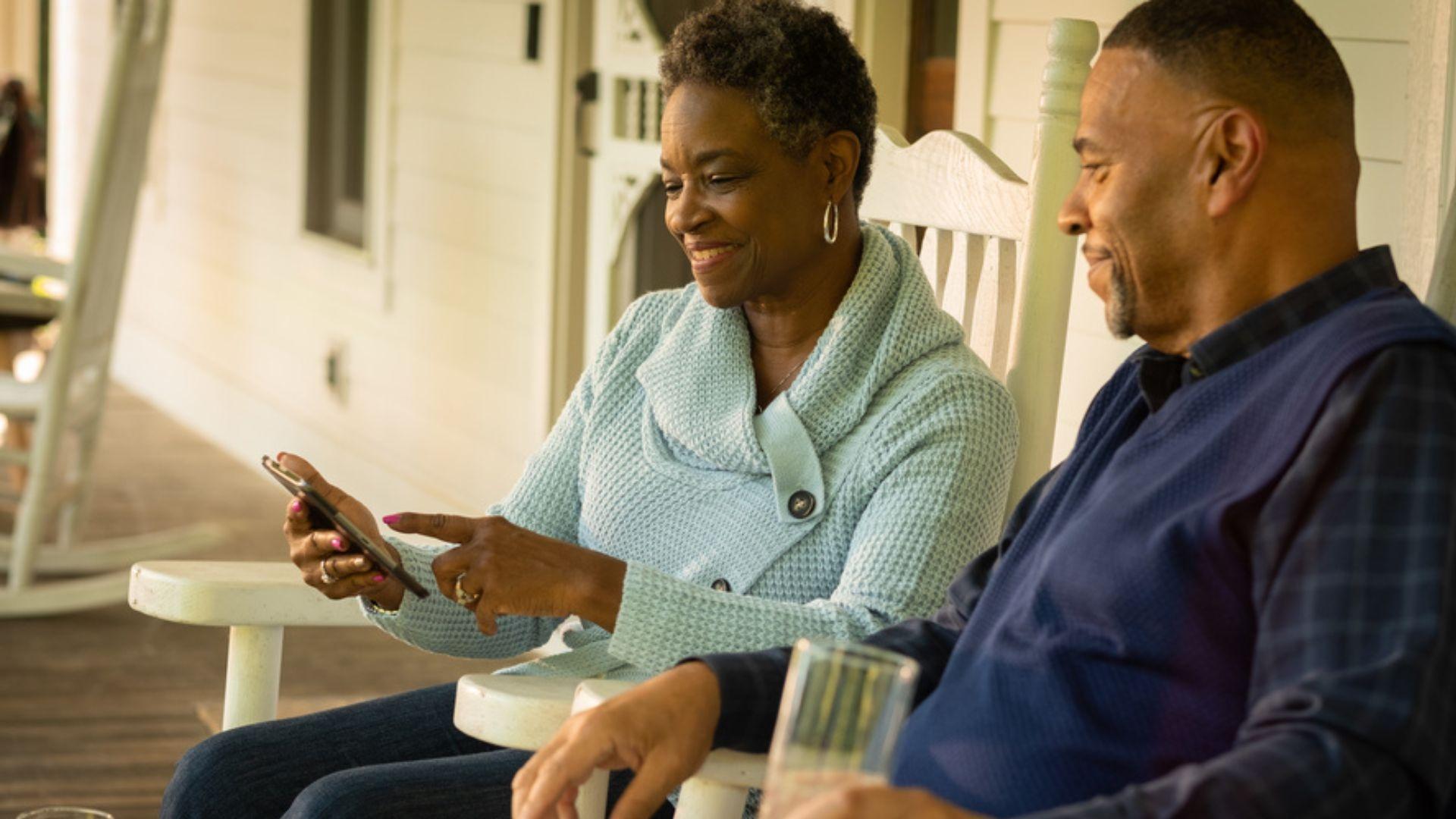 Black couple smiling looking at a phone