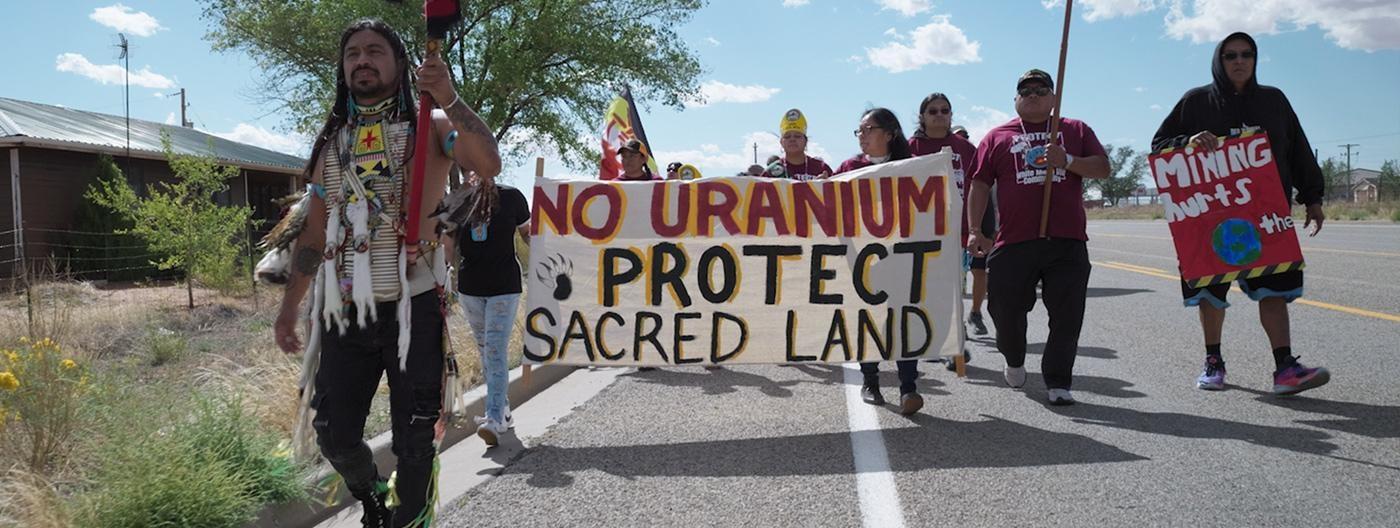Protestors carrying signs, one reads: No Uranium, Protect Sacred Land