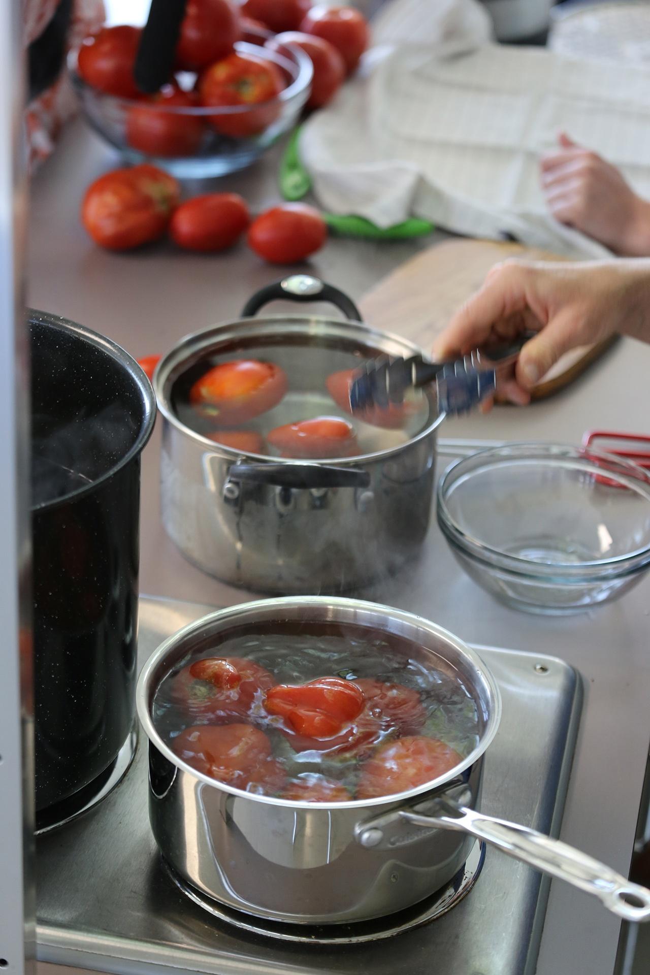 Tomatoes in boiling water and cold water bath.