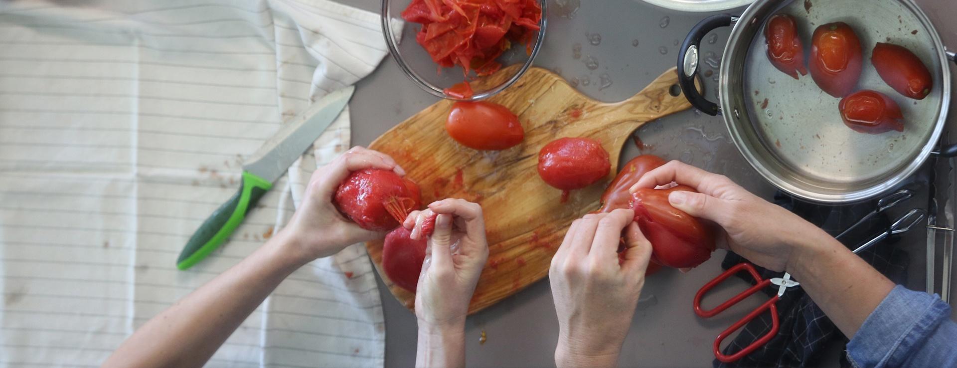 Preparing Salvaterra Select and Red Pear Abruzzese tomatoes for canning by removing the skins.