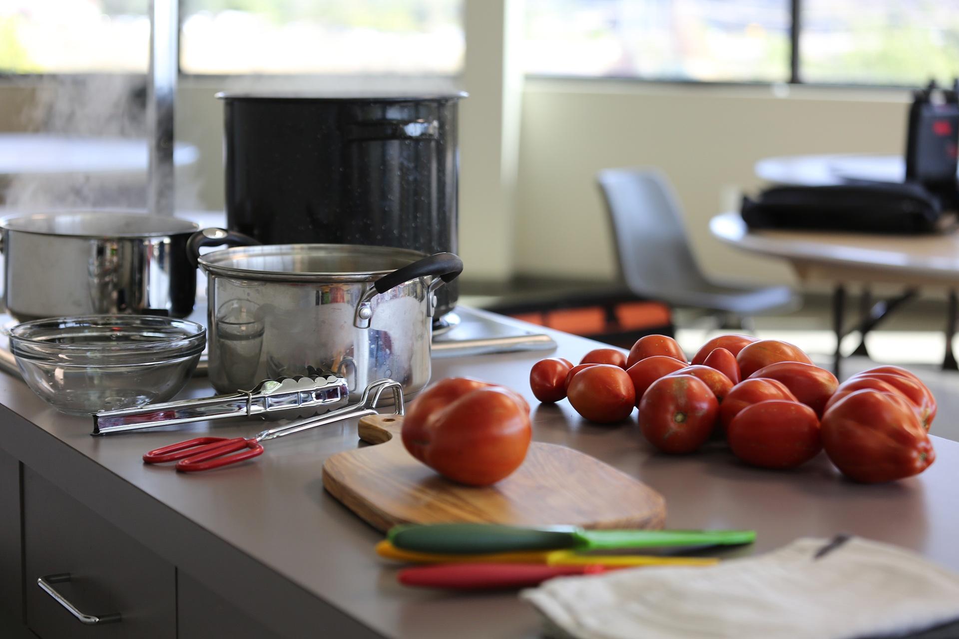 Set up for preparing tomatoes for canning with a large pot of boiling water for sanitizing jars, a pot of boiling water for blanching tomatoes, as well as an ice bath.