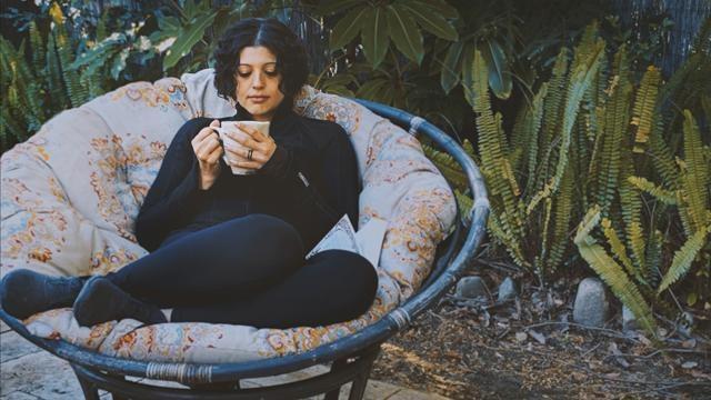 Woman holding her cup of tea outside in a chair