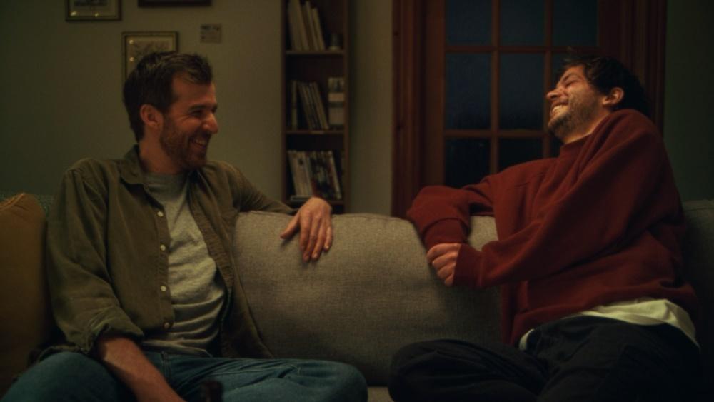 photo of two men smiling and sitting on a couch