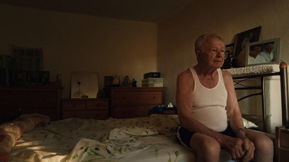 photo of an old man sitting on a bed