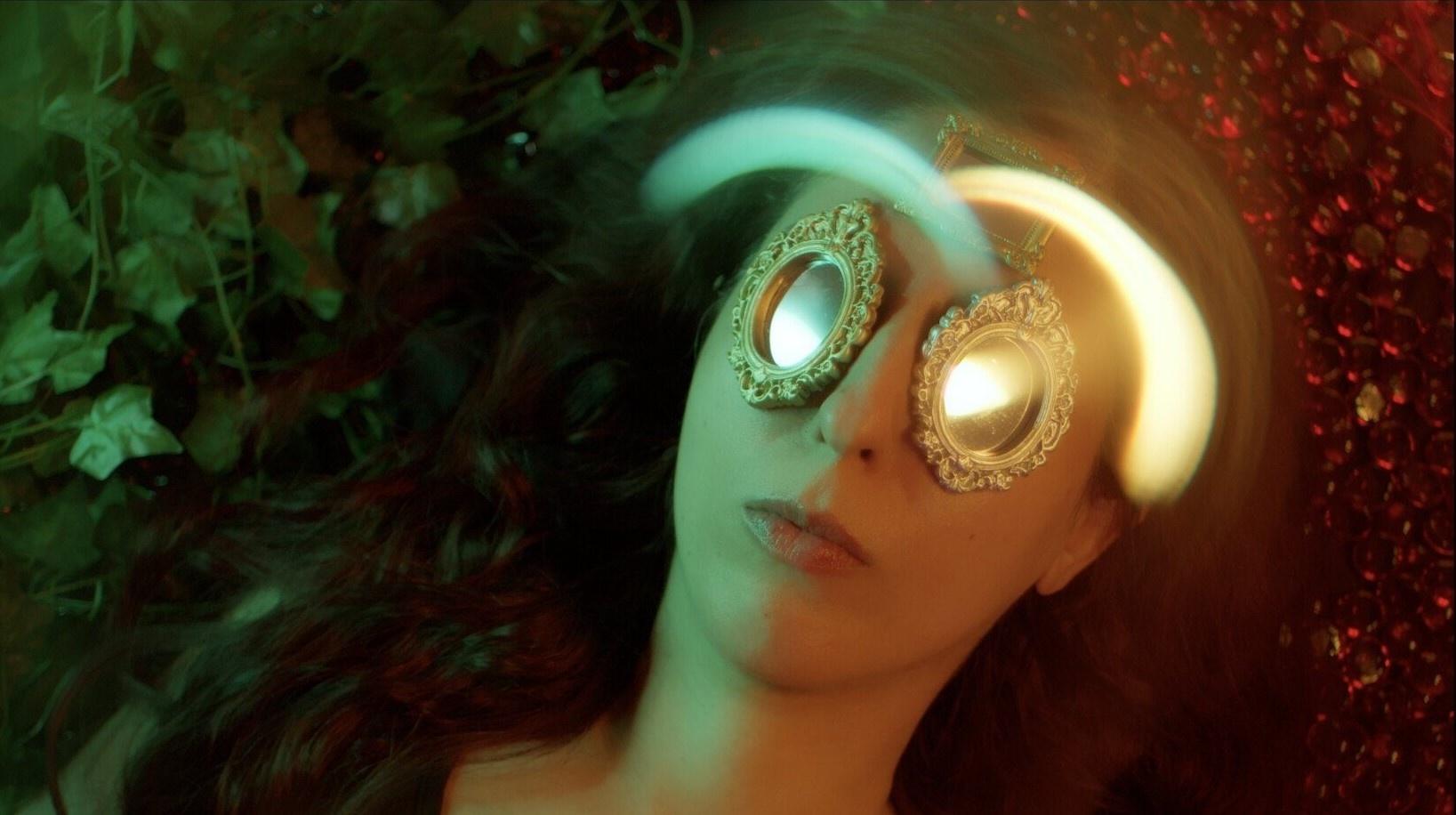 photo of a woman lying down with mirrors on her eyes