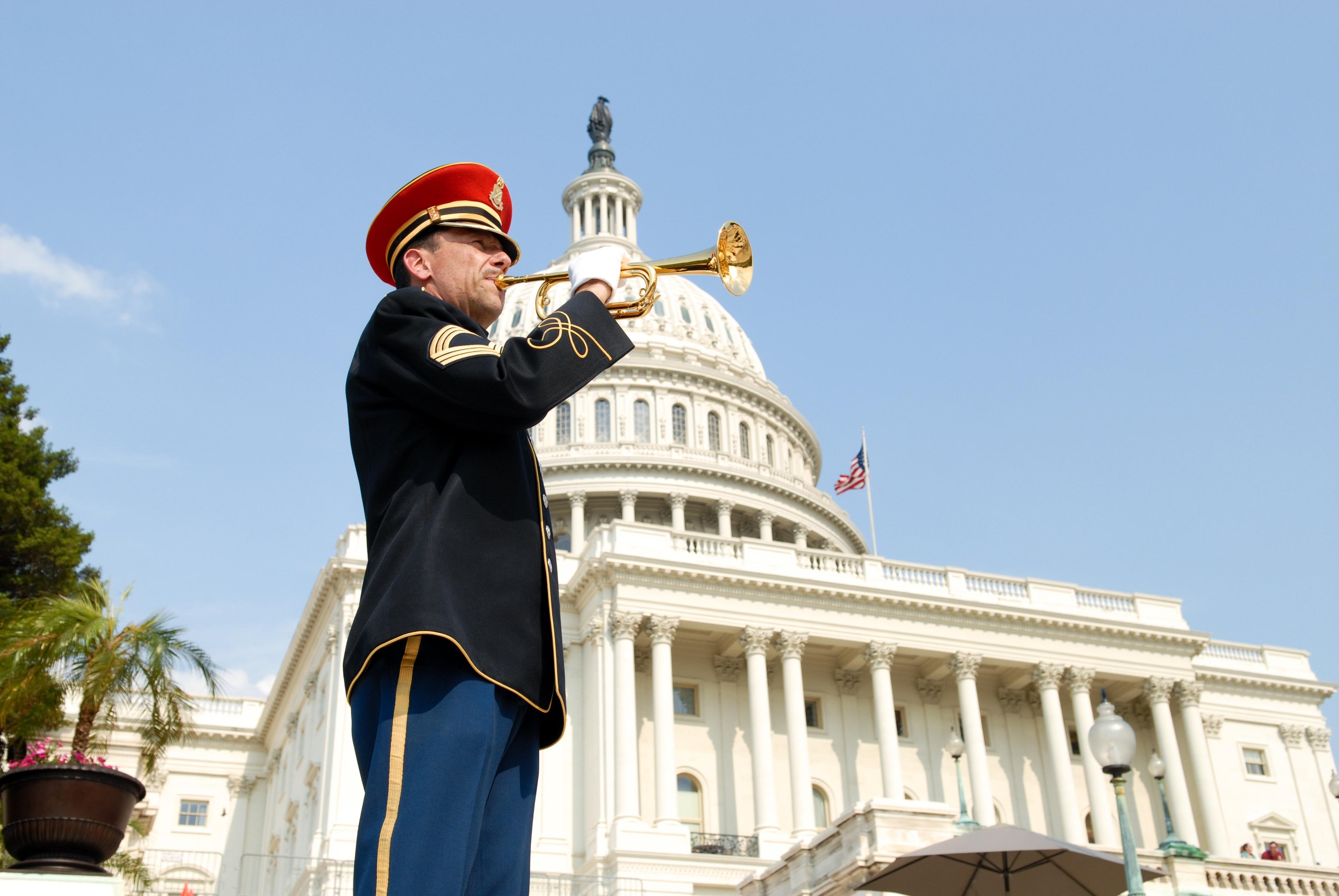 A soldier bugling in front of the U.S. Capitol Building.