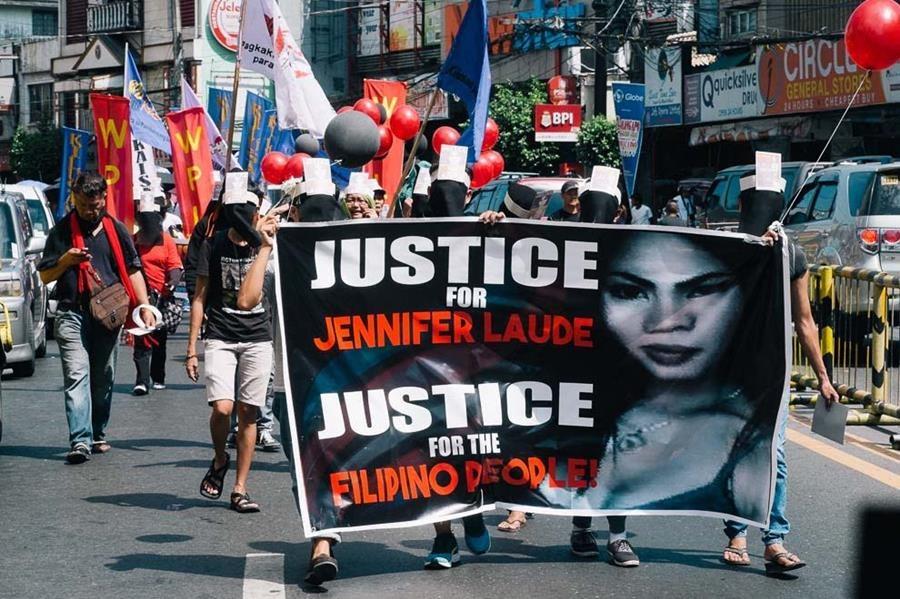 People marching in the street, holding signs that say "Justice for Jennifer" 