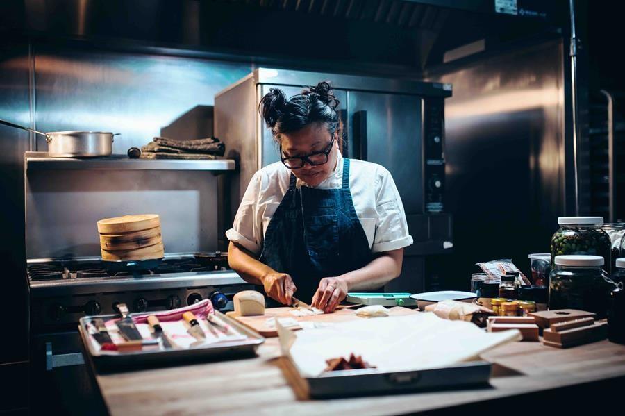 A woman chef chopping in a kitchen.