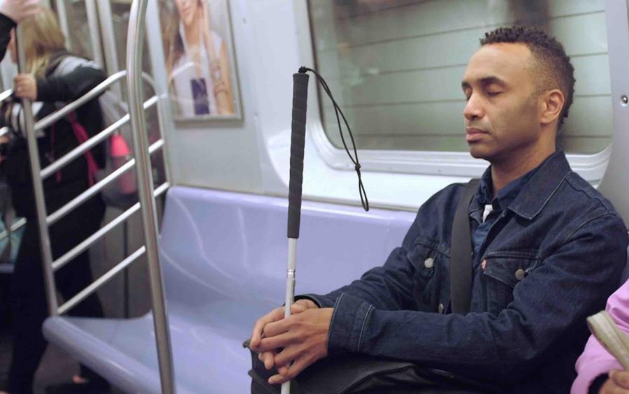 A blind man rides the subway.