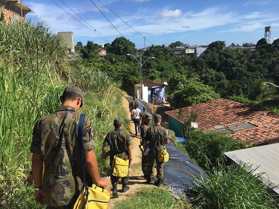 men dressed in military uniforms walking down a path toward a group of houses