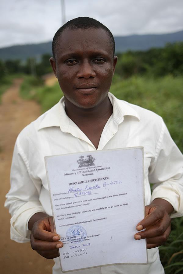 a man holds up a piece of paper that says 'Discharge Certificate'
