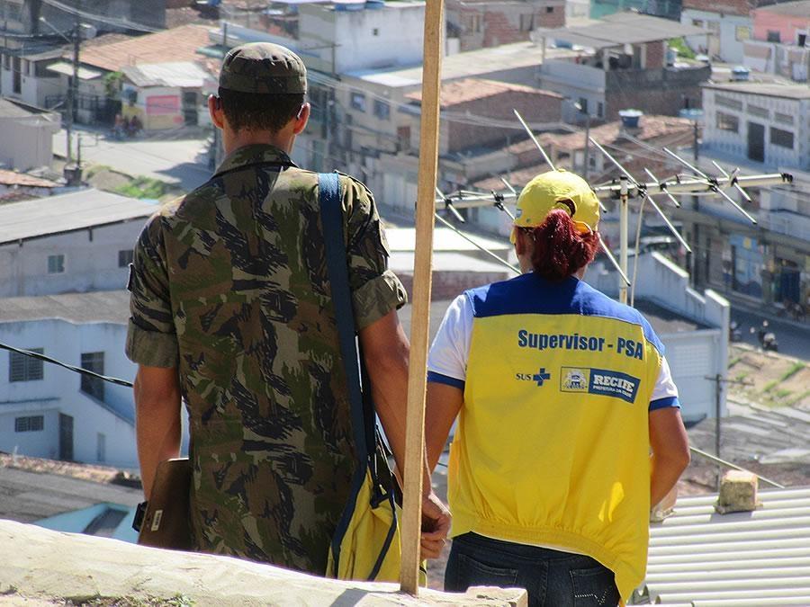 a man in military uniform and a woman wearing a yellow vest with text on it that says 'Supervisor - PSA'