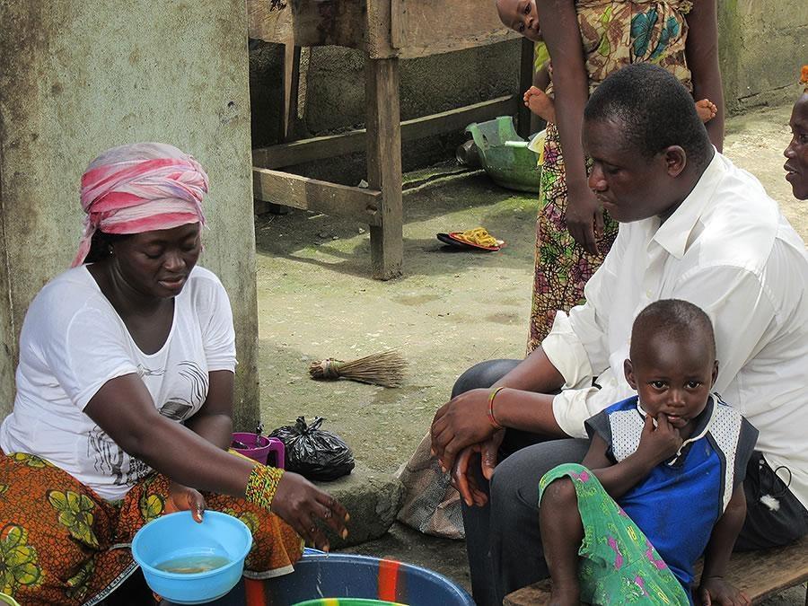 a man and young boy sit across from a woman who is holding a blue plastic bowl