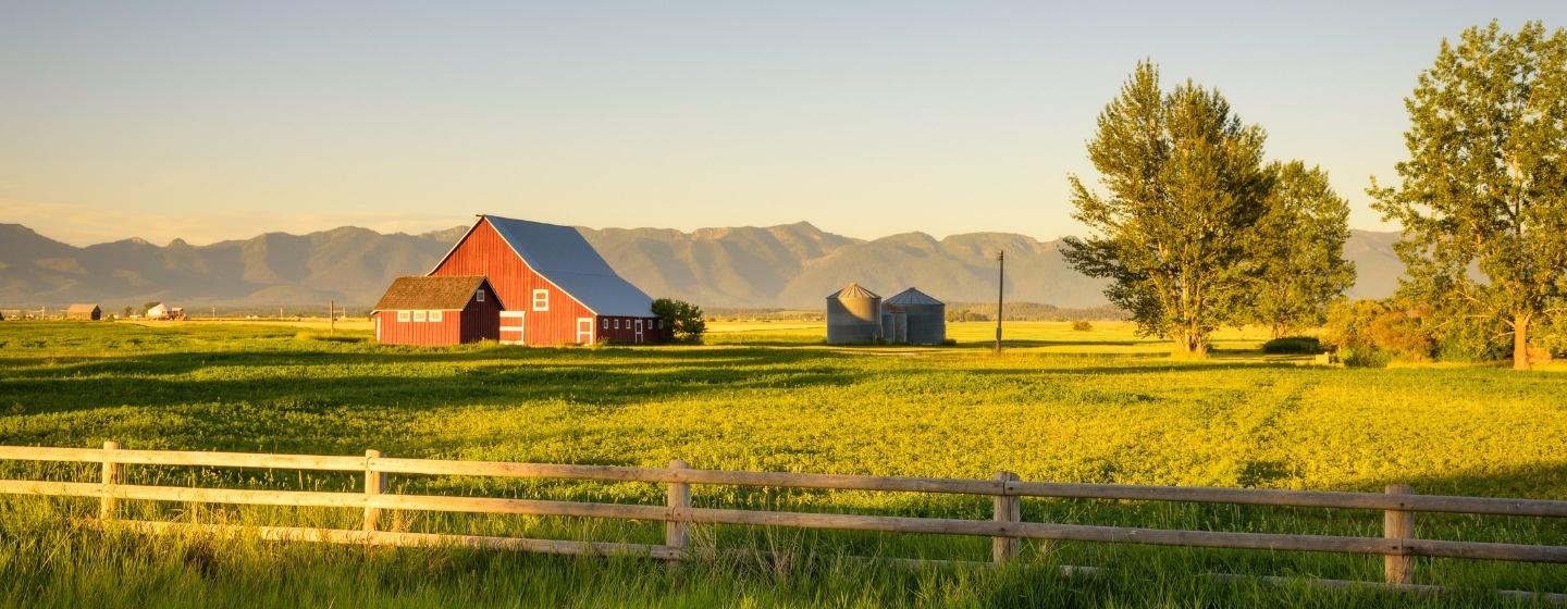 Summer sunset with a red barn and mountains in rural Montana