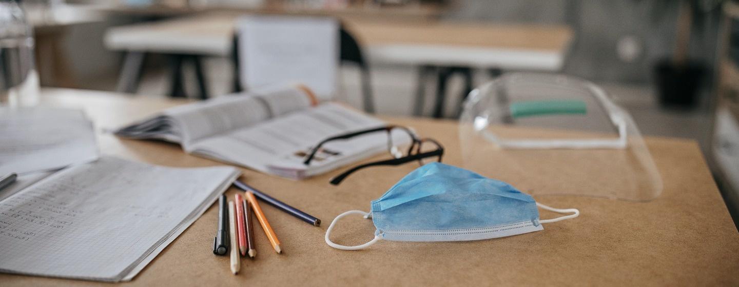 School supplies and face mask on a desk
