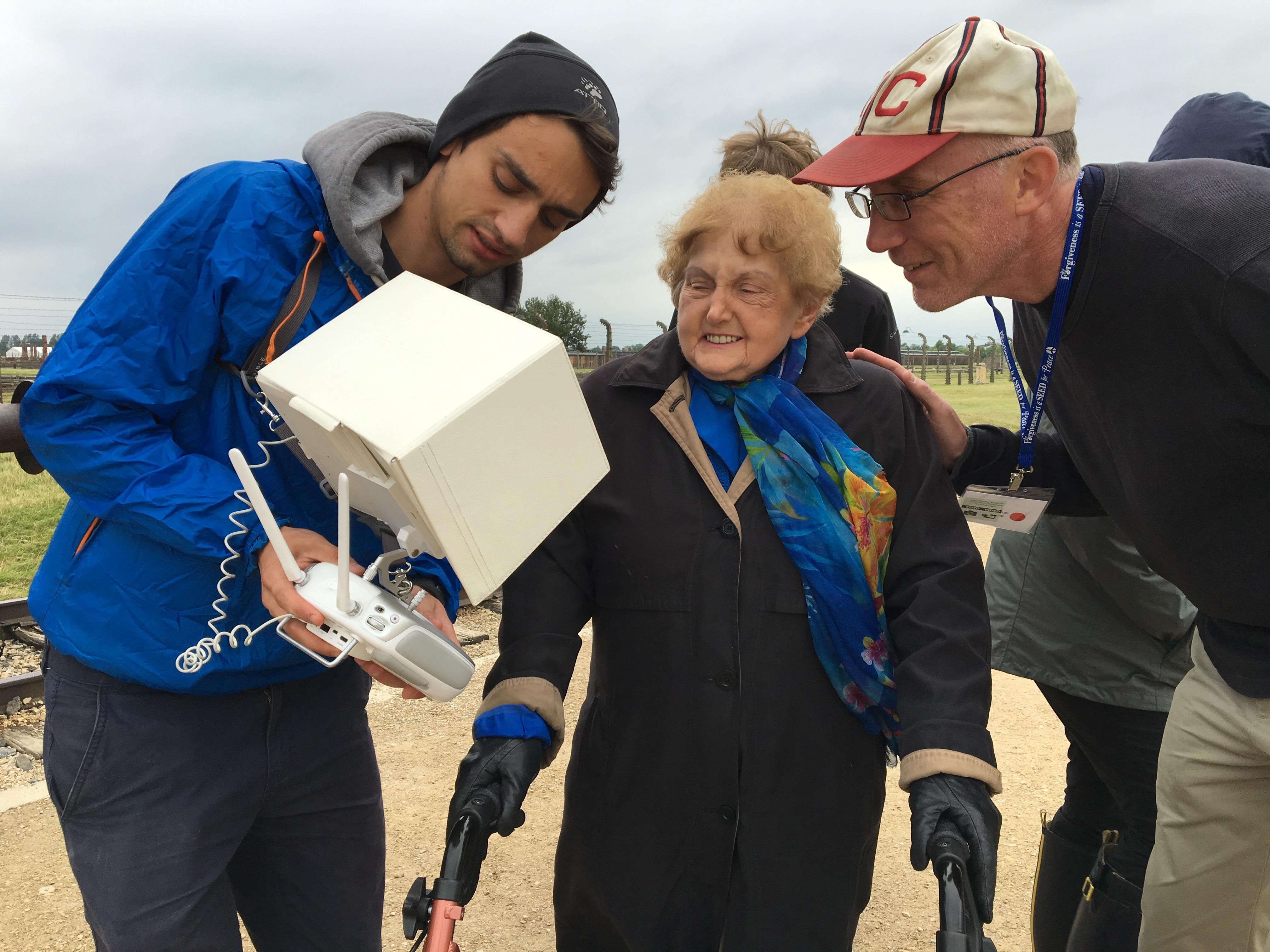 Eva Kor and Ted green looking at drone footate at Auschwitz.