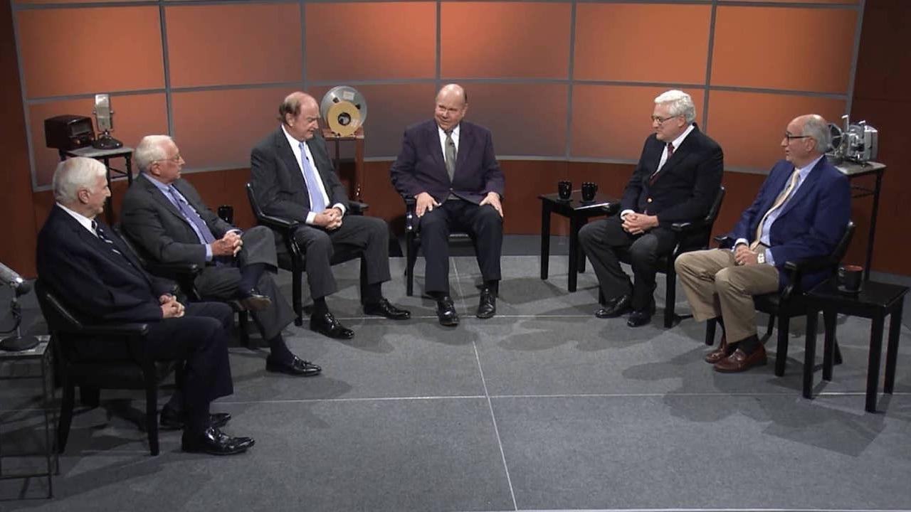 Six men sitting semi-circle on a television set