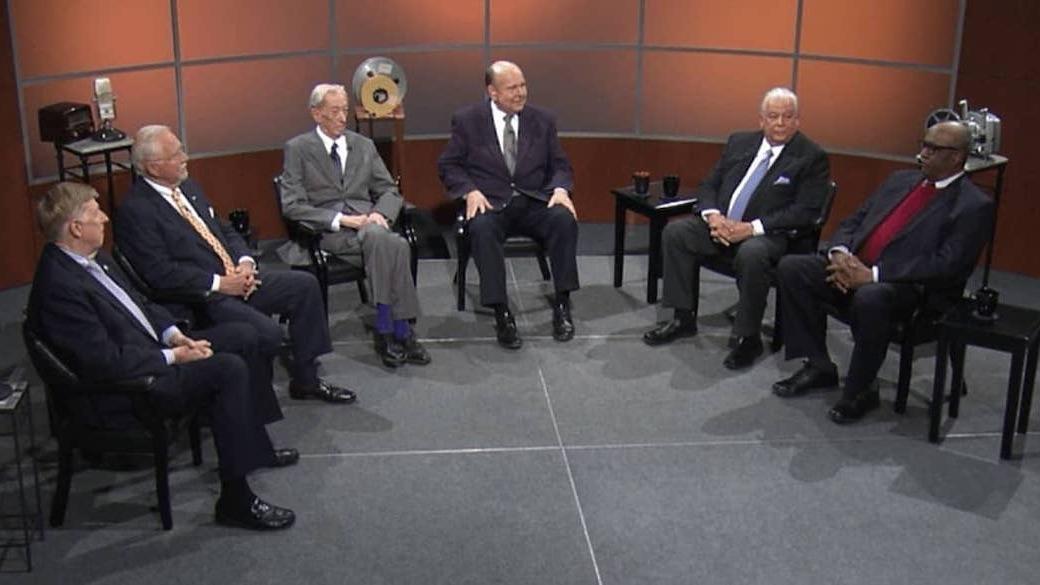 Six men sitting semi-circle on a television set