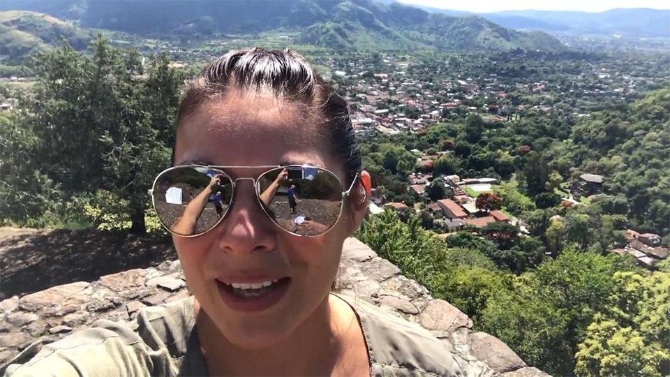 Host Nina Hageness takes a selfie on a mountain with a Mexican village in the background.