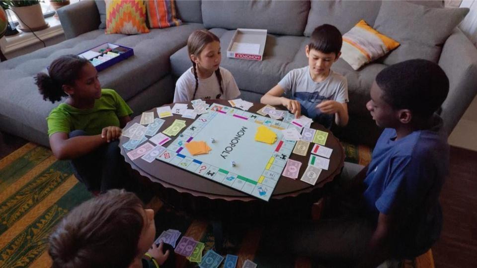 A group of kids playing Monopoly.