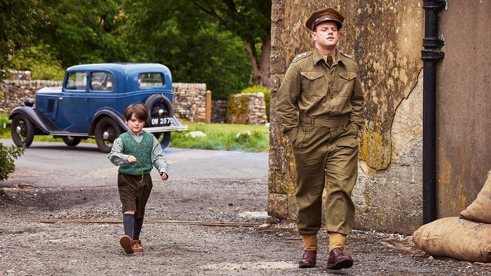 Tristan, wearing an RAF uniform, walks with Jimmy down the street.