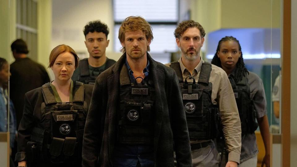 Maigret and other police march through the police stations wearing tactical vests.