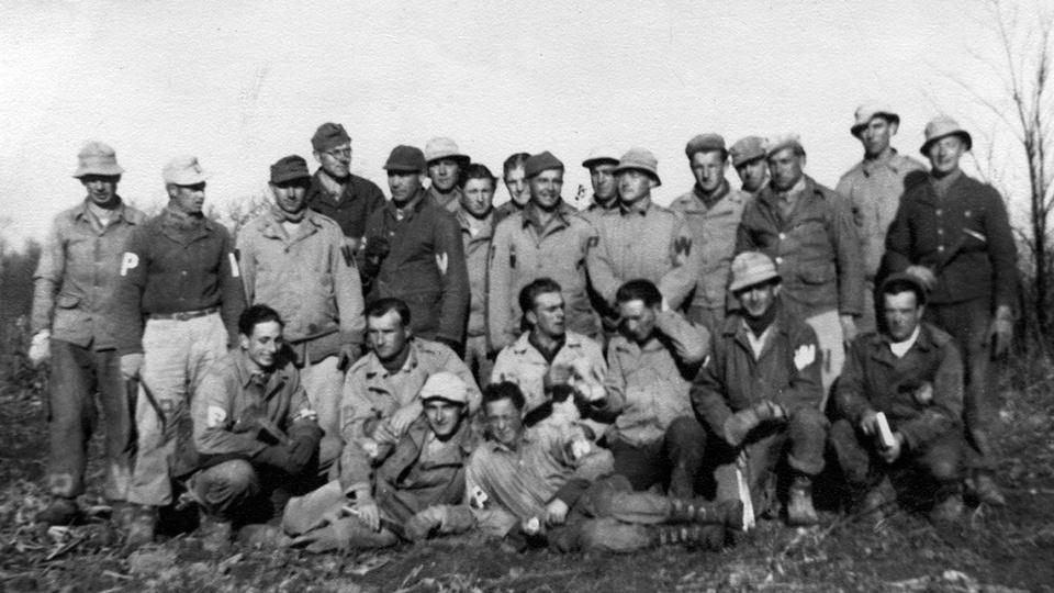A group of POWs posing in a field.