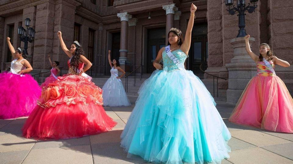 Latinas in quinceañera dresses demonstrating.