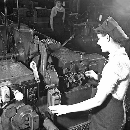 A woman operates a machine in a factory.