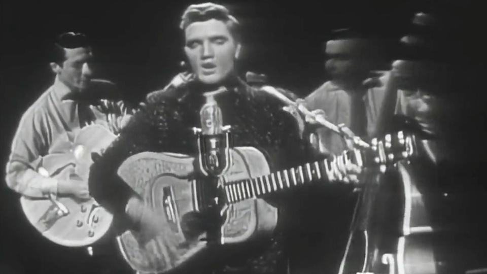 Elvis Presley plays guitar.