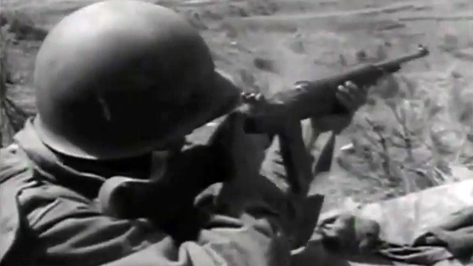 An American soldier in the Korean War firing a rifle.