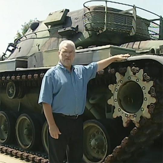 Host Eric Jylha stands next to a tank.